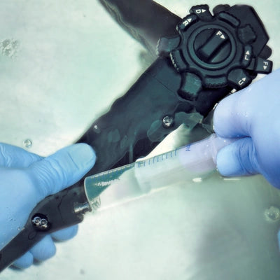 Blauer Handschuh hält medizinisches Gerät mit Spritze – Pflege & Desinfektion