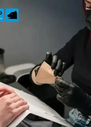 Nagelstudio-Mitarbeiterin mit schwarzen Einweghandschuhen behandelt Hände, Hygieneschutz