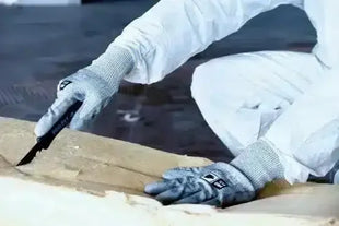 Person mit schnittfesten Schutzhandschuhen und Schutzanzug arbeitet mit Cuttermesser