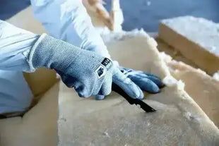 Person mit schnittfesten Arbeitshandschuhen schneidet Dämmmaterial, Schutzkleidung Hygiene