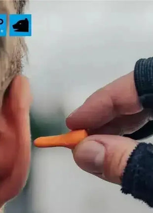 Person setzt orange Gehörschutzstöpsel ins Ohr, Hygiene und Arbeitsschutz Produkt.