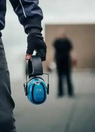 Person hält blaue Gehörschutz-Kopfhörer, Arbeitsschutz, professionelle Hygiene