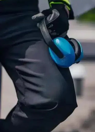 Blaue Gehörschutz-Kopfhörer, gehalten von einer Person mit Arbeitshandschuhen, Arbeitsschutz