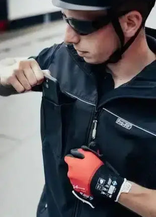 Arbeiter mit Schutzweste, Handschuhen und Helm steckt Ausweis in Brusttasche