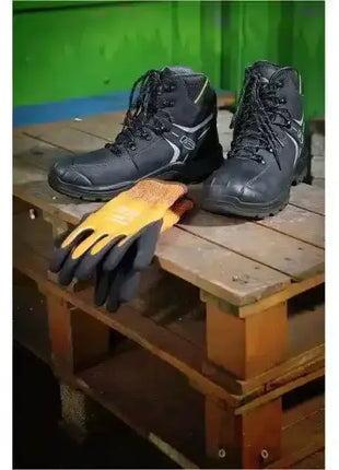 Schwarze Arbeitsschuhe und orange Arbeitshandschuhe auf Holzpalette, Schutzkleidung Industrie