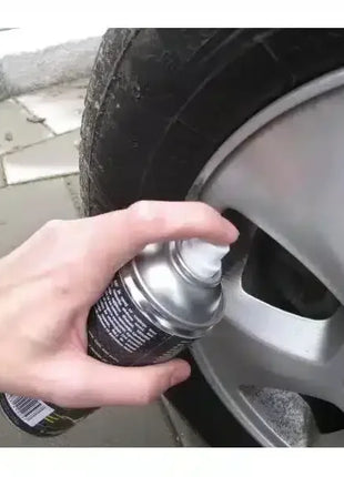 Hand sprüht Reifenpannenspray auf Autoreifen, schnelle Reifenreparatur, Felge sichtbar