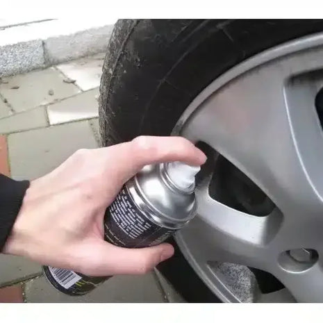 Hand sprüht Reifenpannenspray auf Autoreifen, schnelle Reifenreparatur, Felge sichtbar