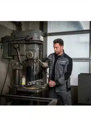 Mann in Arbeitskleidung bedient Industriemaschine in Werkstatt, Metallbearbeitung, Arbeitsschutz