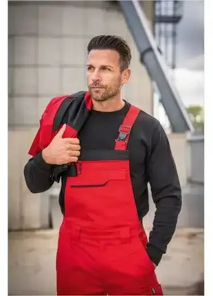Mann in roter Arbeitshose und schwarzem Pullover, professionelle Arbeitskleidung draußen
