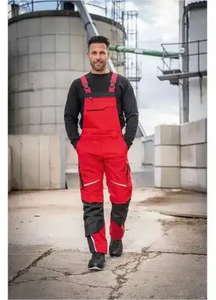 Mann in roter Arbeitshose mit schwarzen Details, Baustellenumgebung, robuste Arbeitskleidung