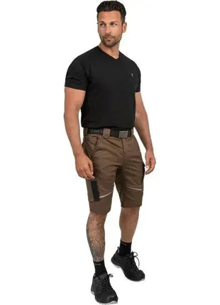 Mann trägt schwarze Funktions-T-Shirt, braune Arbeitsshorts mit Taschen und Arbeitsschuhe, isoliert