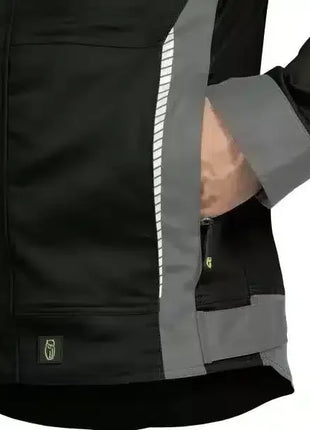 Detail einer schwarzen Arbeitsjacke mit grauen Akzenten und Reflektorstreifen, Hand in Tasche