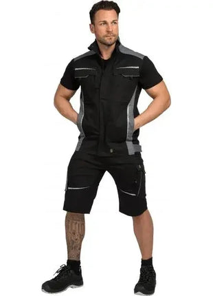 Mann in moderner, schwarzer Arbeitskleidung mit kurzen Ärmeln und Shorts, stehend vor weißem Hintergrund