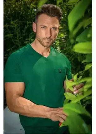 Mann im grünen T-Shirt steht draußen zwischen grünen Pflanzen, Natur, Gesundheitsbewusstsein