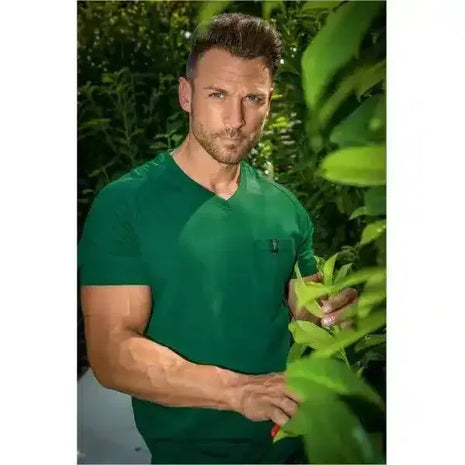 Mann im grünen T-Shirt steht draußen zwischen grünen Pflanzen, Natur, Gesundheitsbewusstsein