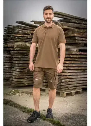 Mann in brauner Arbeitskleidung mit Shorts und Poloshirt, Outdoor, vor Holzstapeln stehend