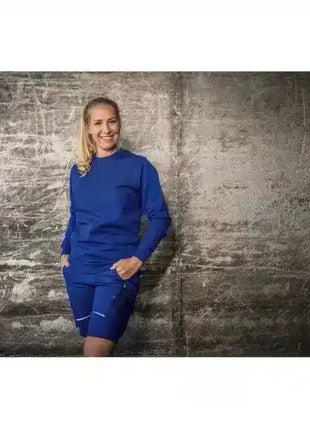 Frau in blauer medizinischer Arbeitskleidung vor neutralem Hintergrund, Hygieneberuf