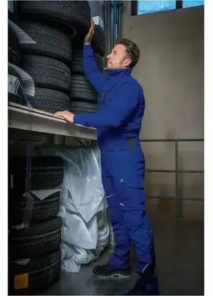 Mann im blauen Overall lagert Autoreifen in einem professionellen Reifenlager