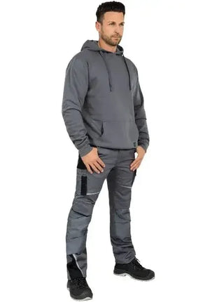 Mann in grauem Hoodie und Arbeitshose, professionelle Arbeitskleidung, stehend, Studioaufnahme
