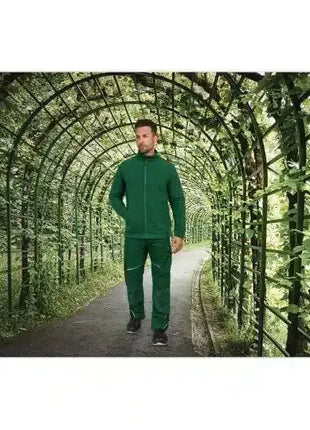 Mann im grünen Trainingsanzug spaziert unter grünem Laub-Tunnel im Park, gesunde Freizeit