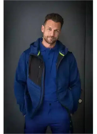 Mann in blauer Arbeitsjacke und Hose, stehend vor dunklem Hintergrund, professionelle Berufskleidung