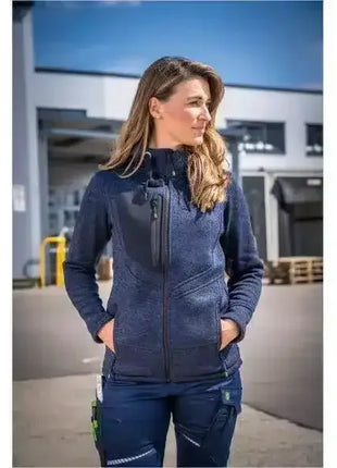 Frau in blauer Arbeitsjacke und Arbeitshose im Außenbereich, professionelle Berufsbekleidung