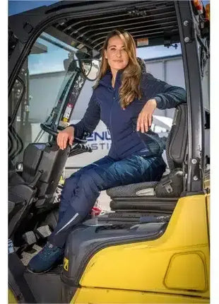 Frau in Arbeitskleidung sitzt auf Gabelstapler, industrielle Umgebung, Berufsbekleidung