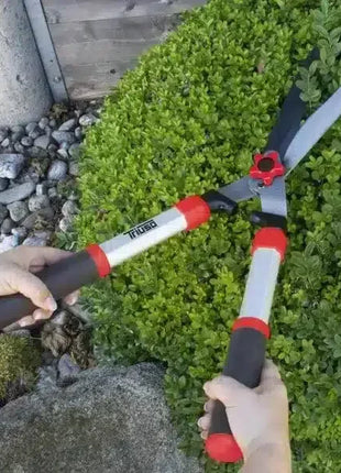 Heckenschere mit ergonomischen Griffen beim Schneiden eines Buschs im Garten, robustes Gartengerät