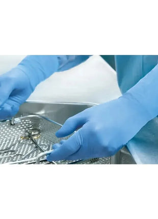 Hände in blauen Einweghandschuhen reinigen medizinische Instrumente im Sterilisator