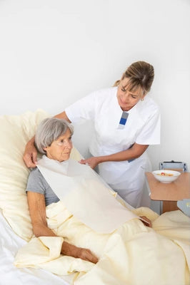 Pflegekraft hilft älterer Frau im Bett mit Inkontinenzprodukt – professionelle Pflege für Senioren