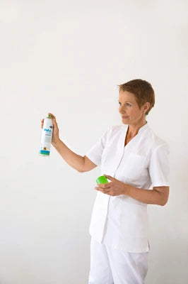 Pflegekraft mit Desinfektionsspray und Handschuhen für medizinische Einrichtungen