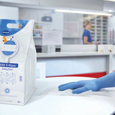 Desinfektionstücher X-Wipes mit blauer Handschuh-Hand in Pflegeumgebung