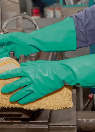 Grüne Schutzhandschuhe bei der Reinigung einer Industriemaschine, hygienisch und robust