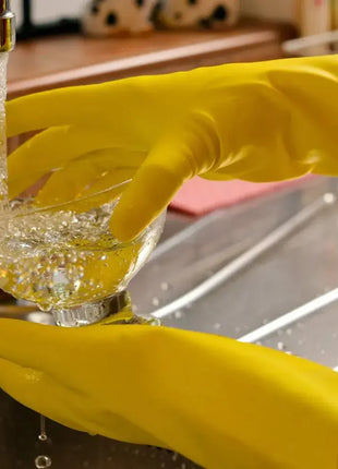 Gelbe Latexhandschuhe beim Spülen eines Glases am Waschbecken, Spritzwasserschutz, Hygiene